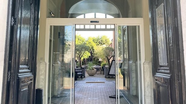 A grand entrance with a glass door leading to a courtyard. - Chateau Fort Lapin (Bruges)
