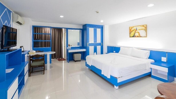 A hotel room with a bed, a desk, a chair, a television, and a painting on the wall. - Relaxed Delux Double | Cozy Stay with Free Parking (Bangkok)
