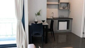 Eine kleine Küche mit Essbereich, einem kleinen Kühlschrank und einem Fenster mit Vorhängen.
