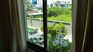 Blick aus einem Fenster auf einen Dachgarten mit Brunnen, Liegestühlen und Schwimmbad.