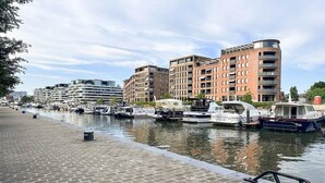 Un canal bordé de bateaux à quai, avec des bâtiments modernes en arrière-plan.
