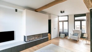 Un salon moderne doté d’une cheminée, d’un téléviseur à écran plat et d’un coin salon confortable.