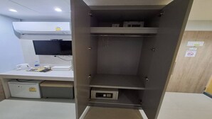 A room with a desk, a computer, a small refrigerator, and a cabinet with a microwave. - Affordable Single | Central Thailand Stay (Bangkok)