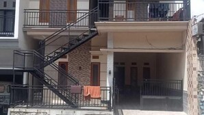 Un edificio de dos pisos con un balcón en el nivel superior, una escalera de emergencia y fachada de piedra.
