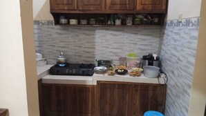 Una pequeña cocina con estufa a gas, armarios de madera y salpicadero de azulejos.