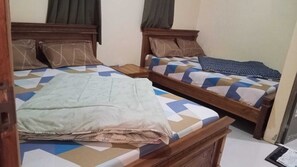 Ein Zimmer mit zwei Holzbett und jeweils mit gemusterten Bettbezügen und Kissen.