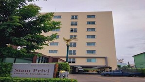 Un immeuble à plusieurs étages portant une enseigne indiquant « Siam Privy Hotel & Residence ».