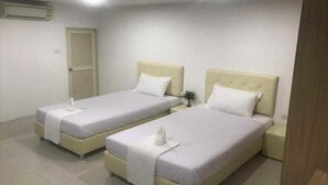 Une chambre d’hôtel avec deux lits simples, une table de chevet avec une lampe et une porte avec un volet.