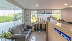 Un espace d’accueil comprenant un canapé, un comptoir de réception et une fenêtre avec des stores.