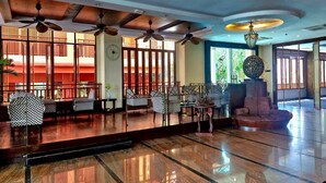 Eine großzügige Lobby mit mehreren Sitzbereichen, Deckenventilatoren und einer großen Dekorationskugel.