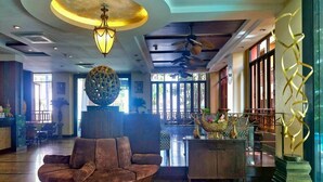 A lobby with a round seating area, a decorative ceiling light, and a reception desk with a decorative bowl. - Twin Escape in Pattaya | Free Pool & Parking (Pattaya)