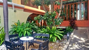An outdoor seating area with benches and a table, surrounded by various plants and trees. - Twin Escape in Pattaya | Free Pool & Parking (Pattaya)