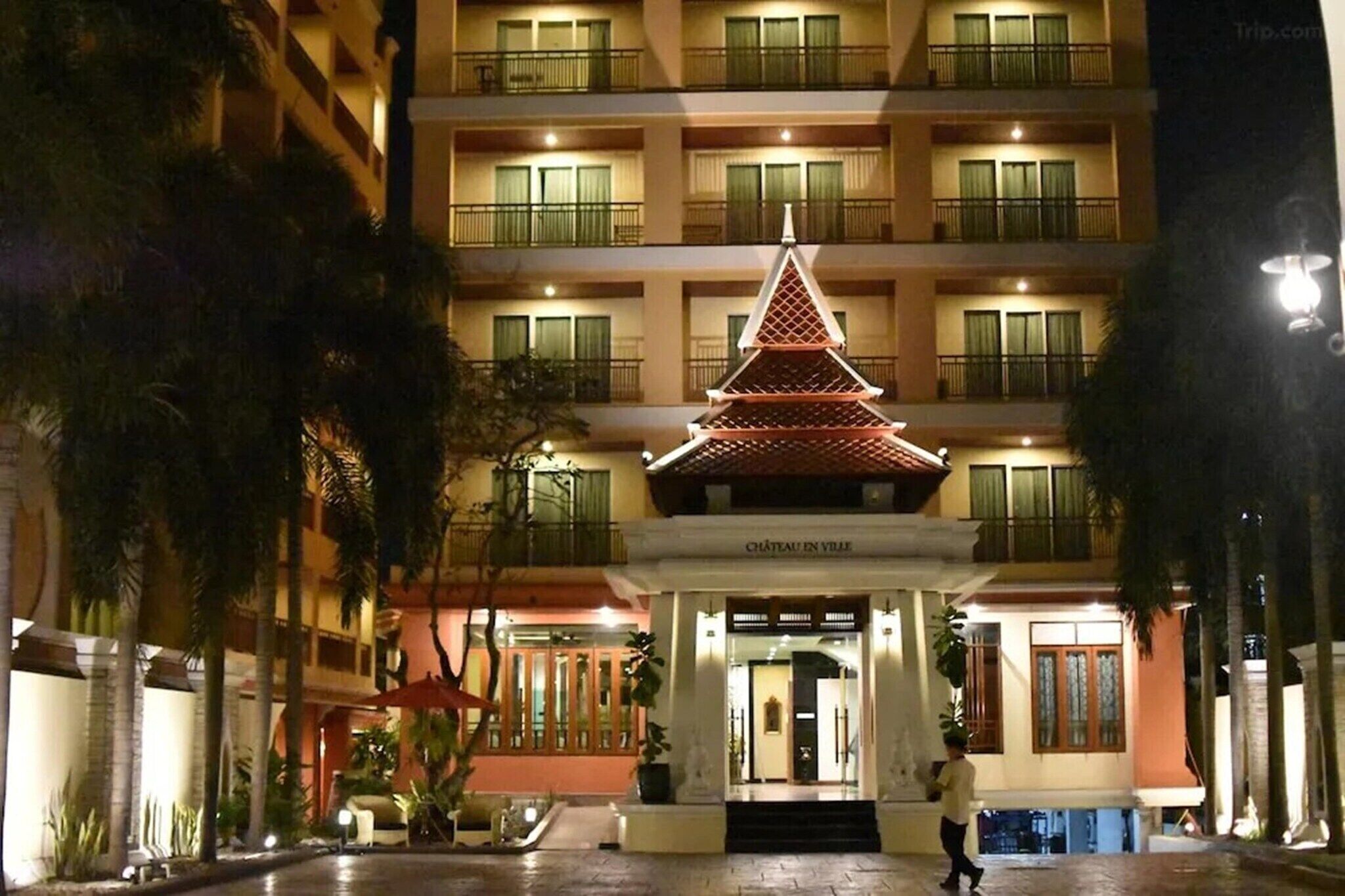A hotel entrance with a traditional pagoda-style structure, multiple balconies, and a well-lit facade.