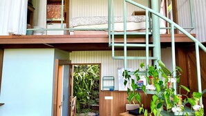 A multi-level room with a bunk bed, a staircase, and a small garden area visible through an open door. - Hilltop Retreat Beneath Mt. Batukaru (Selemadeg)