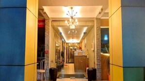 A hotel lobby with a central chandelier, a reception desk, and a seating area with chairs and potted plants. - Smart Solo Stay | Cozy Single Near Clark Airport (Pampanga)