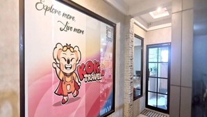 A hallway with a framed poster advertising 'Kong Travel' and a QR code. - Smart Solo Stay | Cozy Single Near Clark Airport (Pampanga)
