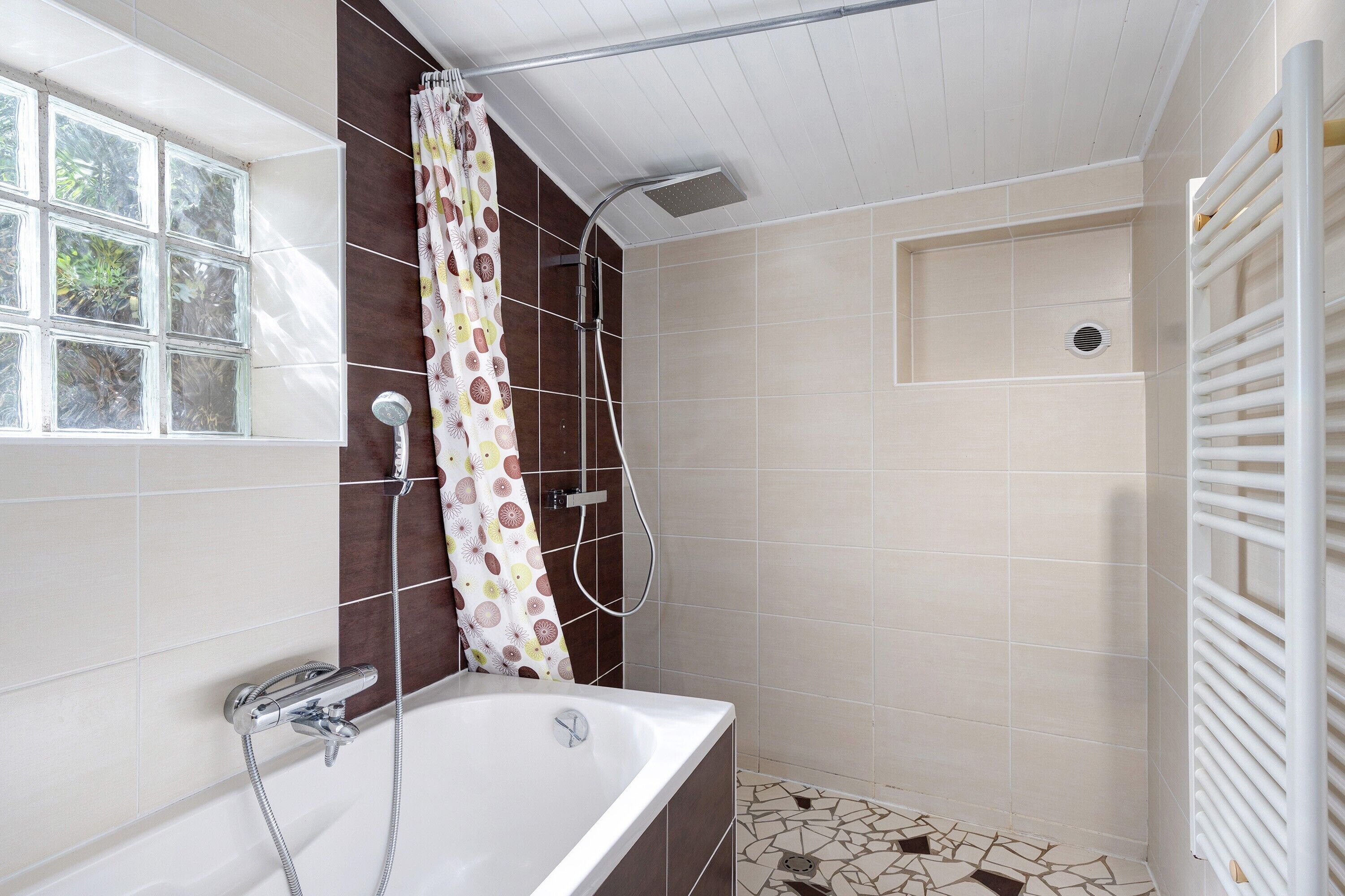 Une salle de bain avec une baignoire, une douche et une fenêtre.