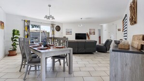 Una sala moderna con comedor, sofá gris, televisor y decoración mural.