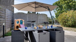 Un patio al aire libre con una mesa, sillas, una parrilla y un área de juegos para niños.