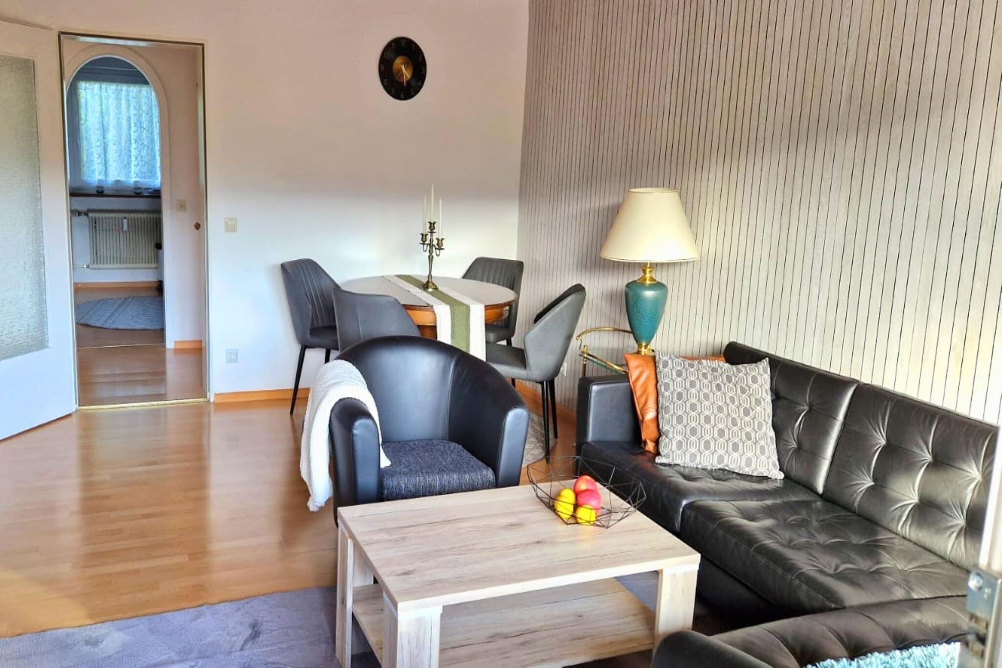 Een moderne woonkamer met een bank, stoelen, een eettafel en een lamp.