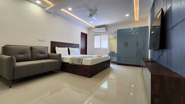 Une chambre moderne avec un lit, un canapé, une armoire et un téléviseur.