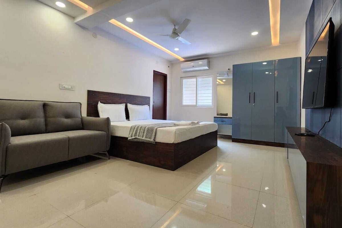 Une chambre moderne avec un lit, un canapé, une armoire et un téléviseur.
