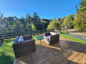 A wooden deck with wicker furniture and a small table. - Relaxing summer house in Motueka Valley (Motueka)