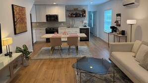 A modern kitchen with white cabinets, a black microwave, and a dining area with a table and chairs. - 1940’s Beauty near downtown, medical center and UH (Houston)