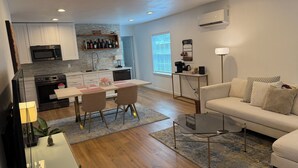 A modern kitchen with a dining area, a living room with a sofa, and a TV. - 1940’s Beauty near downtown, medical center and UH (Houston)
