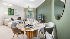 Un comedor moderno con una mesa redonda, sillas tapizadas en gris y una planta central.