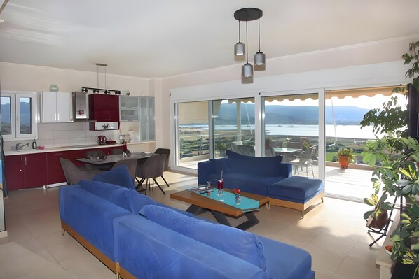 Una sala de estar moderna con un sofá, una mesa de centro y vistas a un lago a través de amplios ventanales.