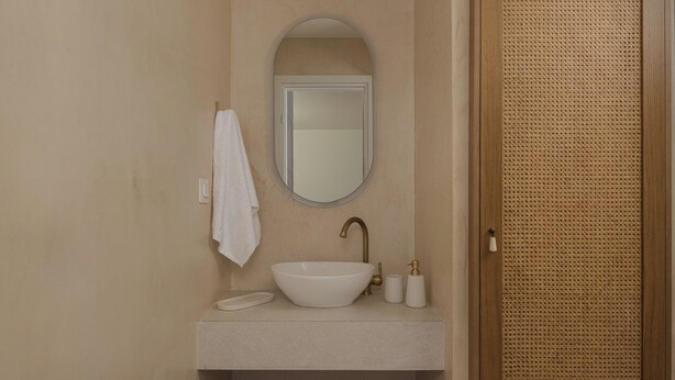 Un baño con un lavabo blanco, un espejo y una toalla colgada en la pared.