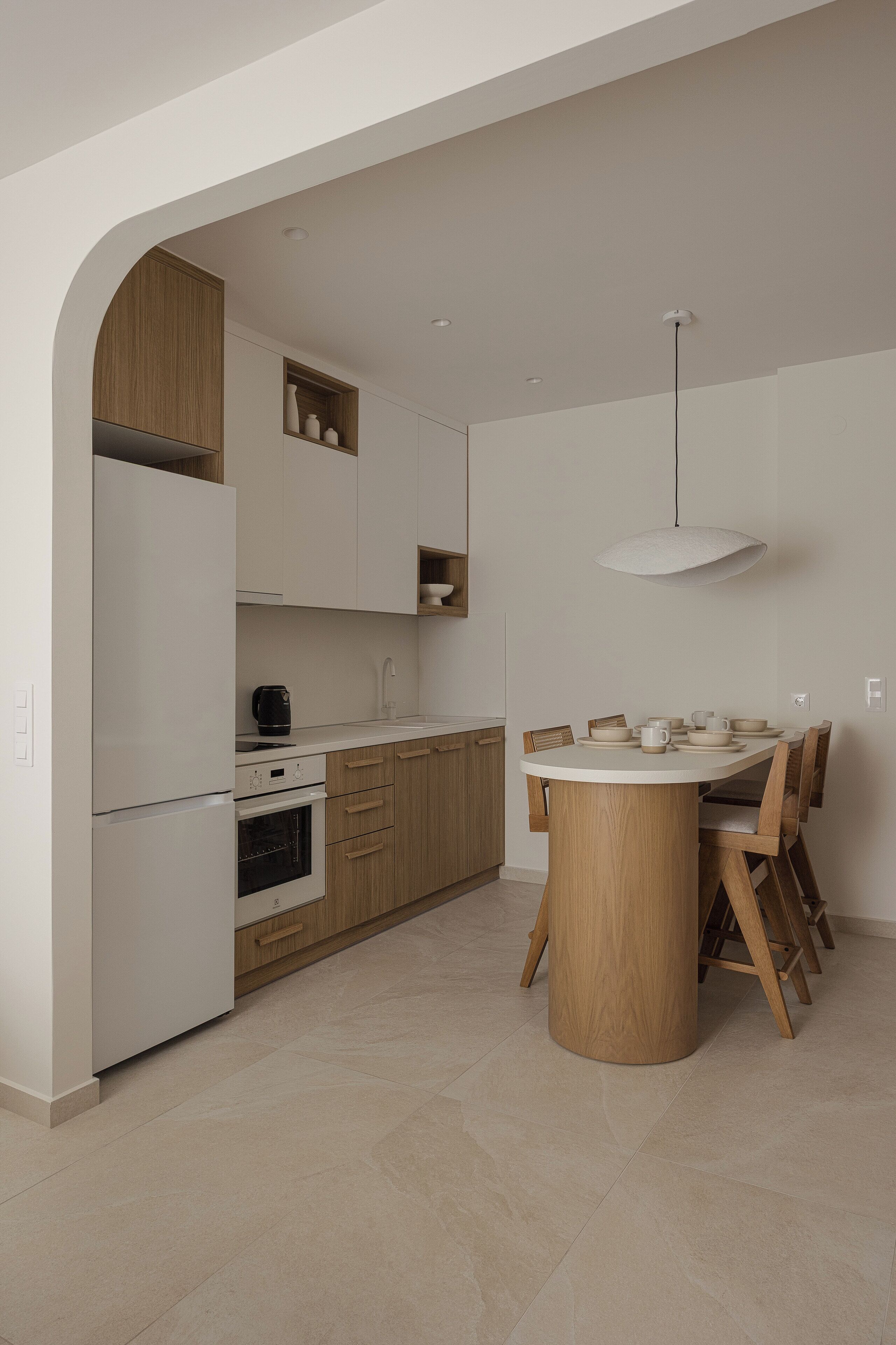 A modern kitchen with white appliances, wooden cabinets, and a central island with chairs.