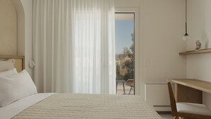 A bedroom with a bed, a chair, a desk, and a view of the outdoors. - Swan Lake (Ioannina)
