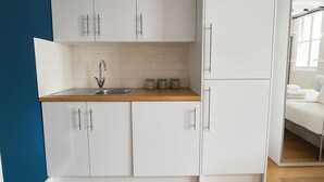 A modern kitchen with white cabinets, a wooden countertop, and a sink. - Modern Studio Flat in Hammersmith (London)