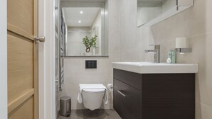 A modern bathroom with a toilet, sink, and mirror. - Modern Studio Flat in Hammersmith (London)