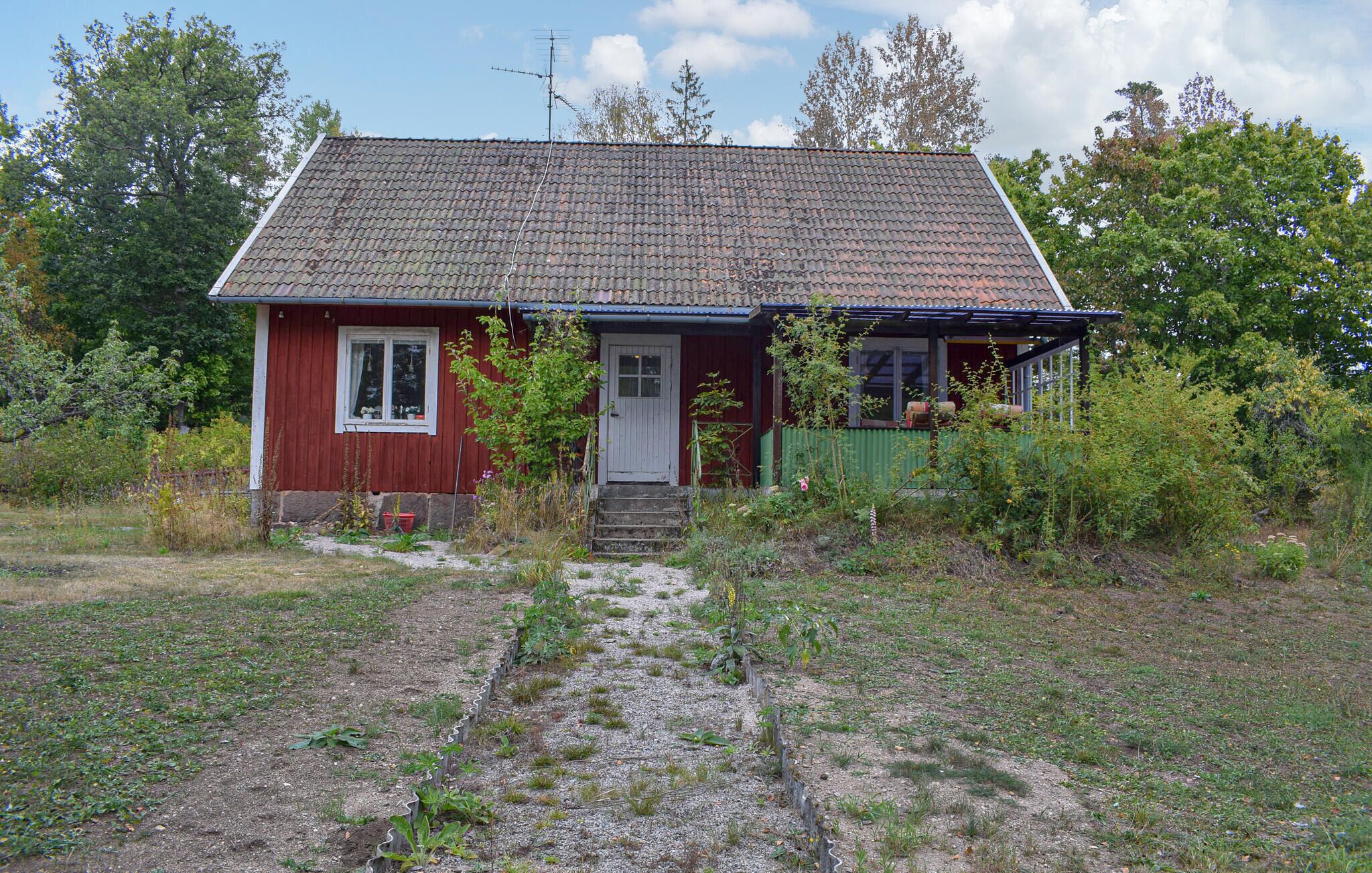 Une petite maison de plain-pied, à l’extérieur rouge et au toit recouvert de tuiles.