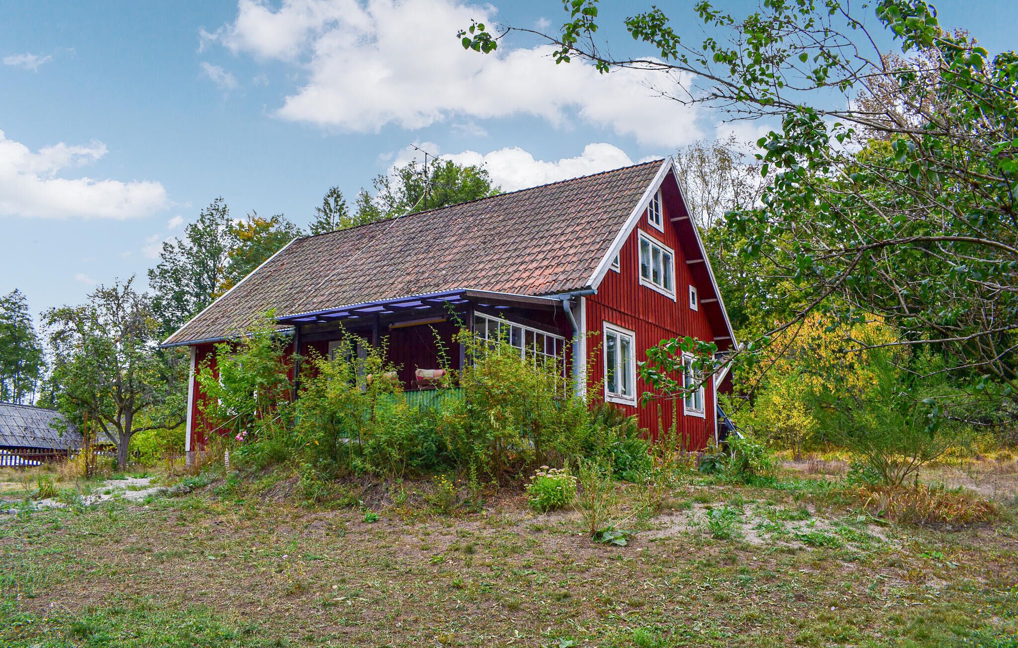 A red wooden house with a sloped roof and a covered porch.