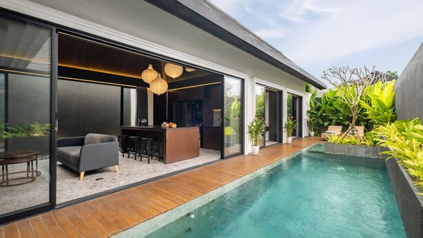A modern house with a swimming pool, a dining area with a bar, and a large glass door leading to a patio. - Modern 3bedroom villa with calm surrounding (Kabupaten Gianyar, Bali)