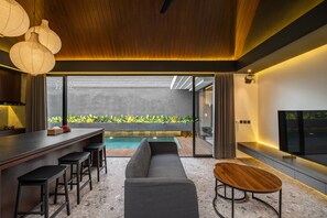 Una cocina moderna con barra, un sofá gris y una mesa de madera.
