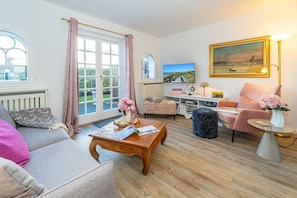 A cozy living room with a sofa, armchair, coffee table, and a TV. - Altstadttor 17 - Holiday apartment under thatch for up to two people in (Sylt)
