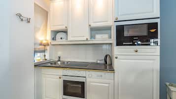 A modern kitchen with white cabinetry, a built-in oven, a microwave, and a sink.
