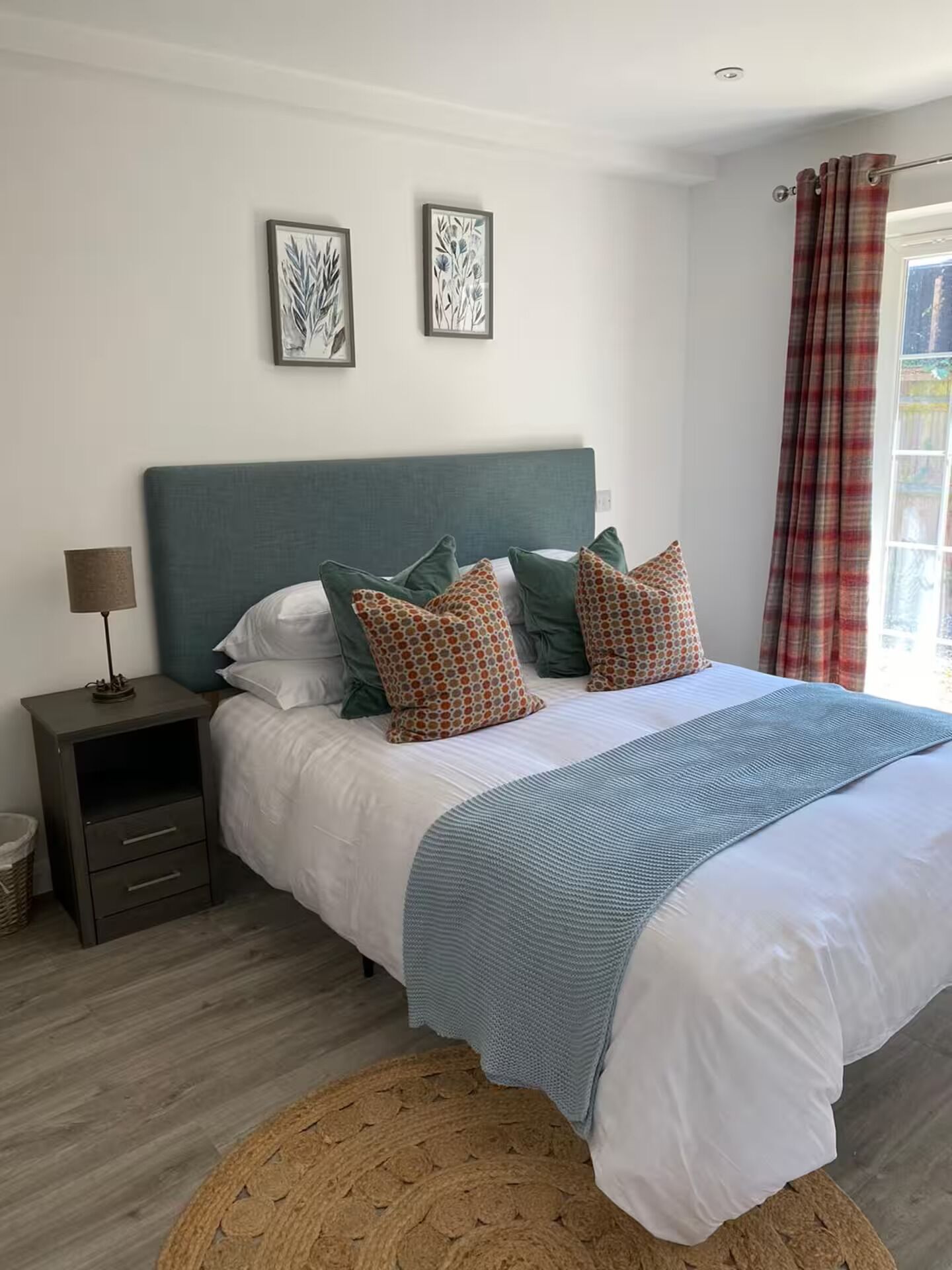 A bedroom with a bed, pillows, a nightstand, a lamp, and two wall art pieces.