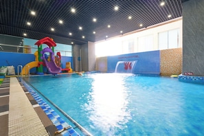 Ein Innenpool mit Wasserrutsche und Spielbereich.