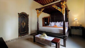 A traditional four-poster bed with a canopy, a wooden nightstand, and a bench with a floral arrangement. - Madesimon Villa (Payangan)