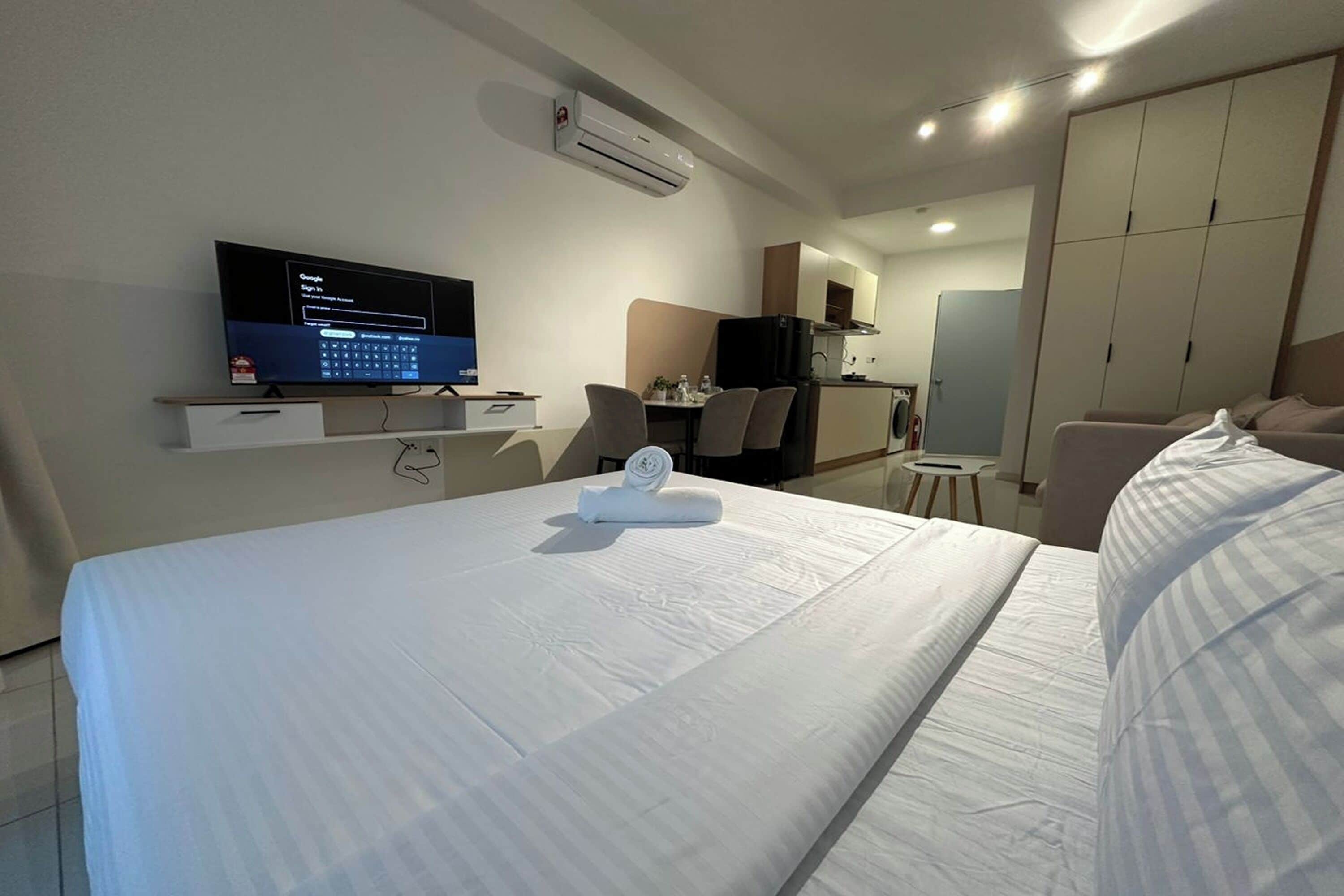 Ein Hotelzimmer mit Bett, Fernseher, Schreibtisch und einer Küchenzeile.