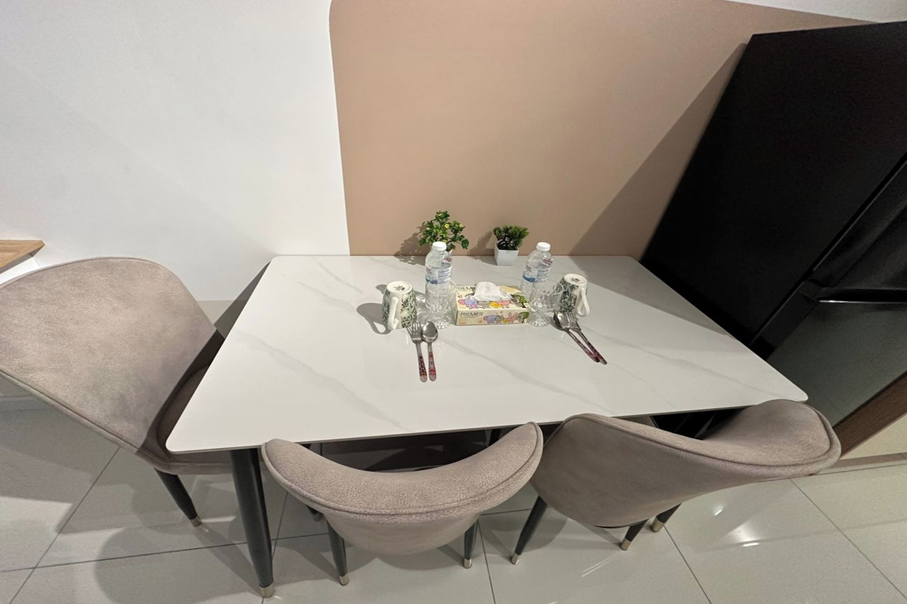 Un comedor con una mesa blanca, dos sillas grises y una pequeña planta en maceta.