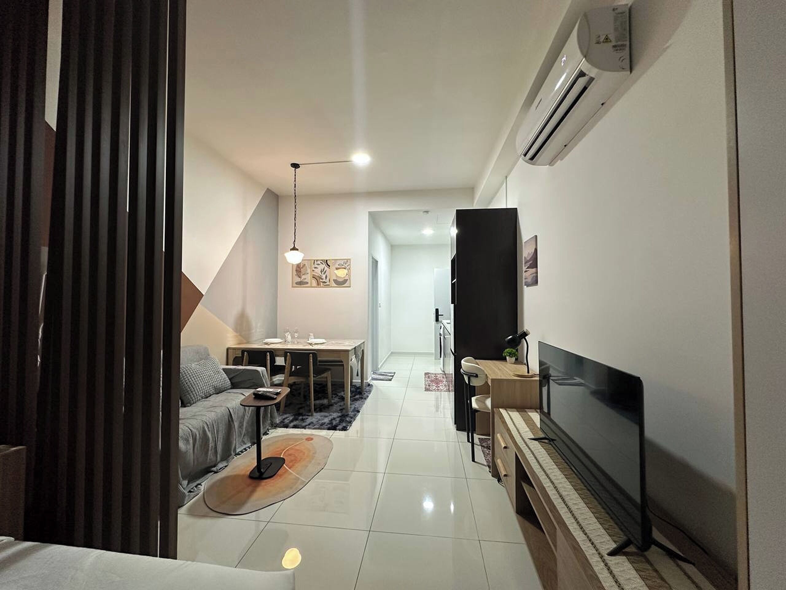 Una sala de estar moderna con sofá, mesa de comedor y televisor.
