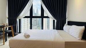 Une chambre d’hôtel avec un grand lit, un bureau et une vue sur de hauts immeubles.