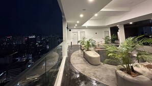 Un intérieur moderne avec un balcon incurvé donnant sur une vue panoramique de la ville la nuit.